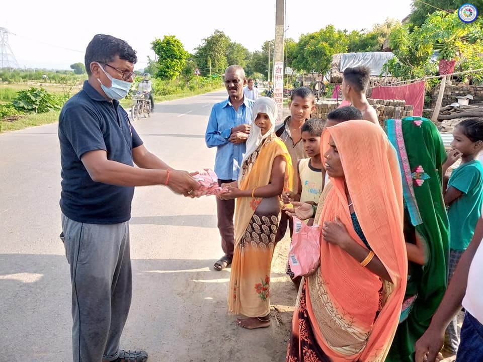 A team member distributing cooked ration packets to families impacted by Ganga river flood