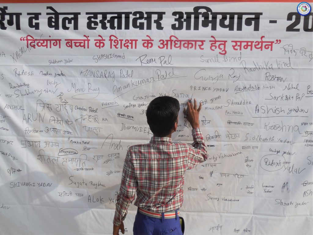 A school kid signing the signature campaign banner for equal education for Children with Disabilities (CwDs)